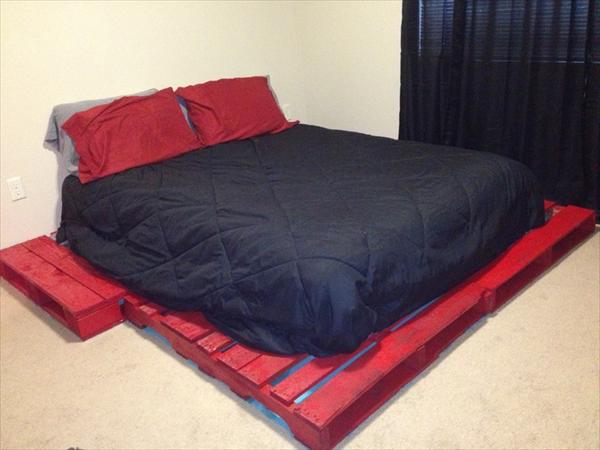 Un lit avec des palettes peintes en rouge