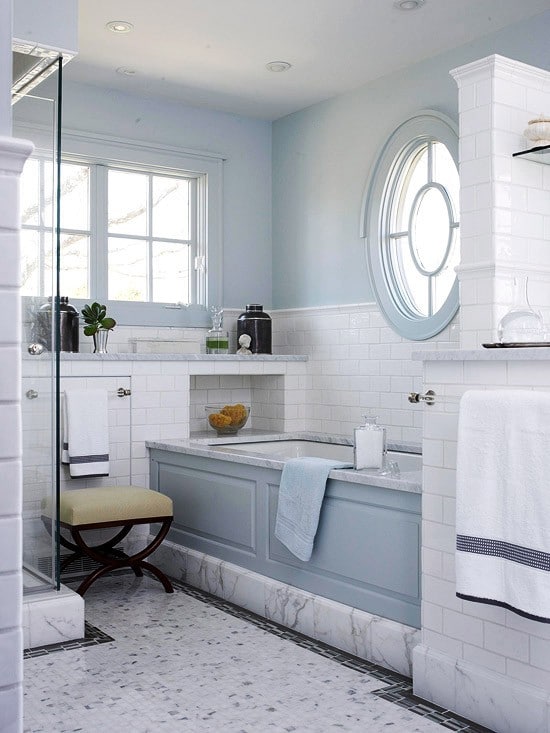 une salle de bain bleu clair avec un oeil de boeuf au dessus de la 