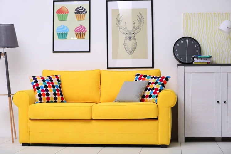 Canapé jaune avec ses coussins à pois colorés avec son mobilier fonctionnel et pratique pour une pièce utile et confortable
