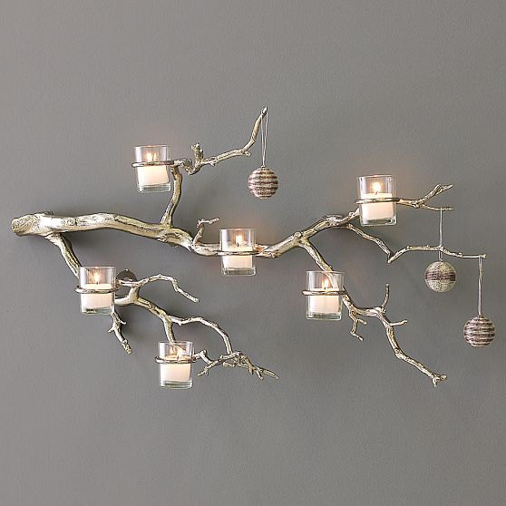 Branche décorative utilisée ici comme support pour bougie contre un mur gris